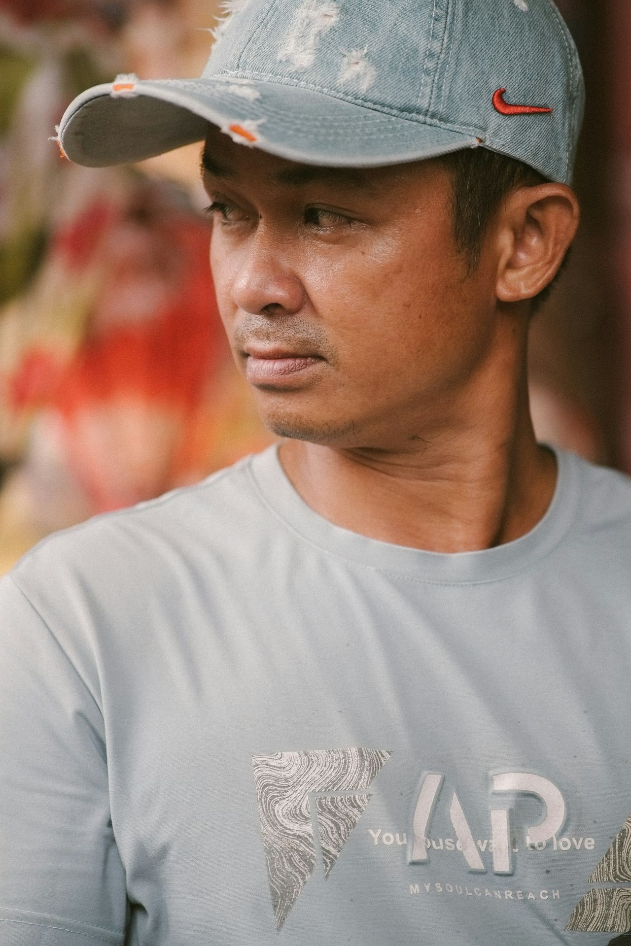 A man in a cap and t-shirt looks sideways.